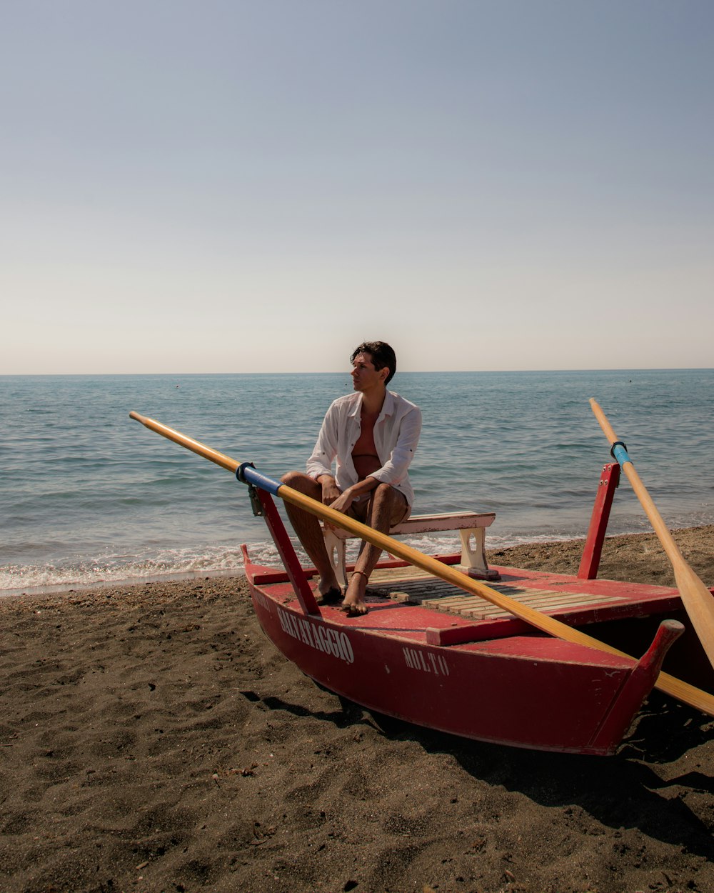 a man sitting on a boat on the beach