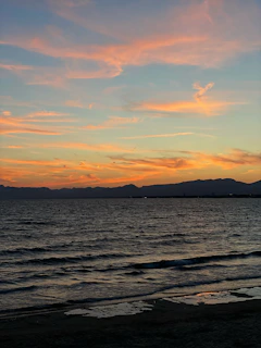 Sunset view over a serene Balinese beach with soft orange and blue ocean hues.
