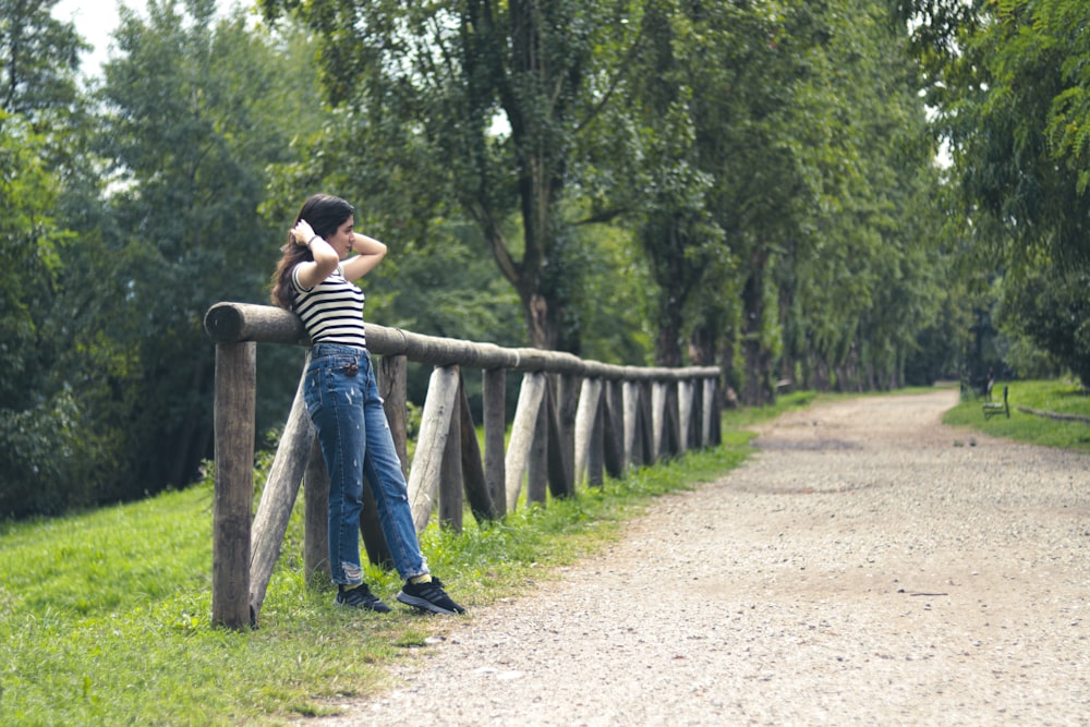 a person leaning against a fence on a dirt road