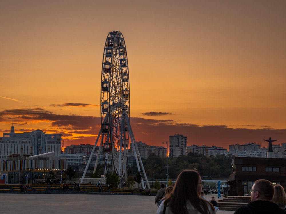 a ferris wheel in the distance with a sunset in the background