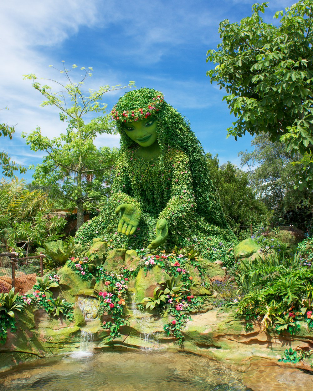 a statue of a frog sitting on top of a lush green field