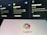 The image shows a blurred background with displays of Google services such as Google Flights, Google Hotels, and Google Maps. In the foreground, there is a clear view of a screen displaying the Copilot logo with colorful overlapping shapes.