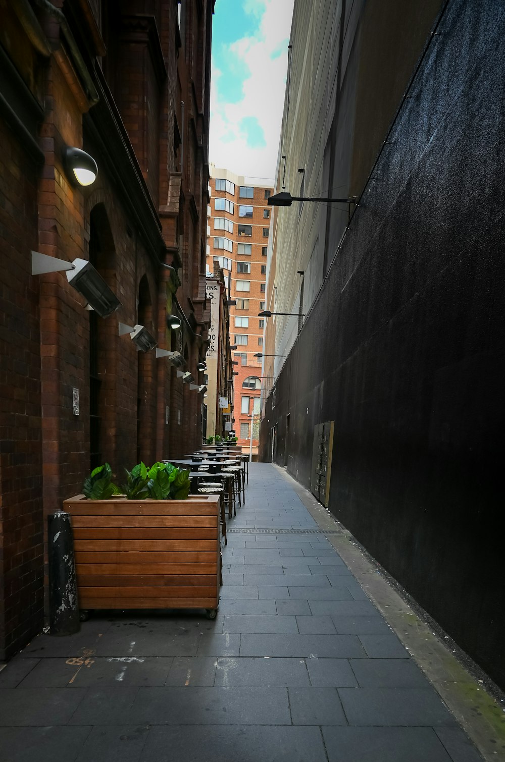 Eine schmale Stadtstraße, gesäumt von hölzernen Pflanzgefäßen