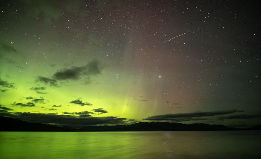 um céu verde e roxo com estrelas acima da água