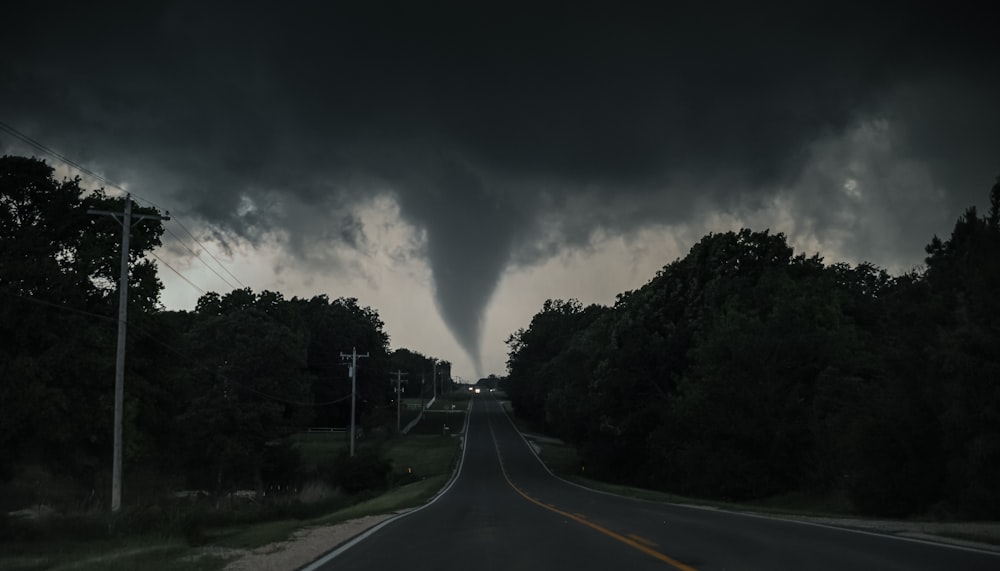 a large tornado is seen in the sky over a road