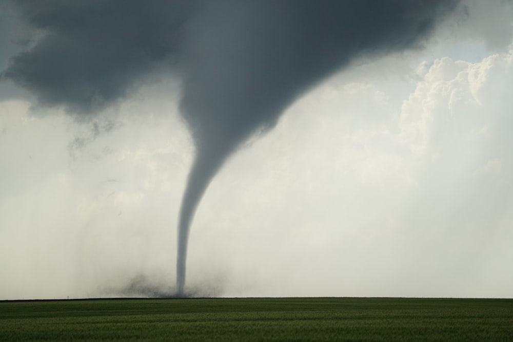 a large tornado is seen in the sky over a green field