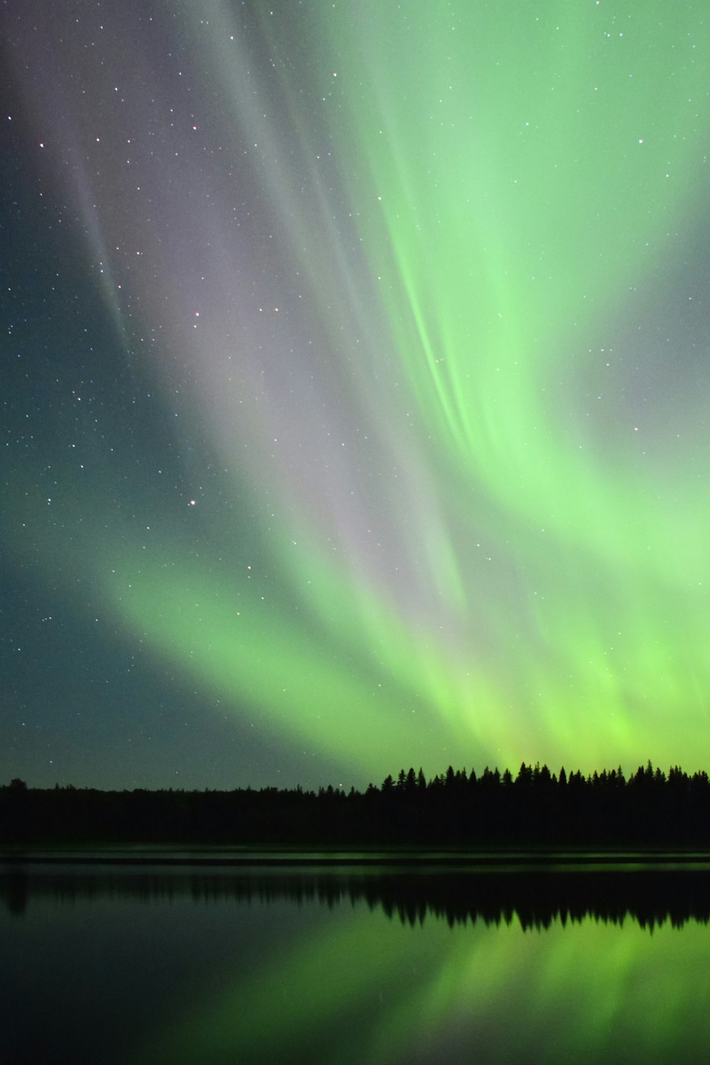 Ein grünes und violettes Polarlicht bohrte sich über einen See