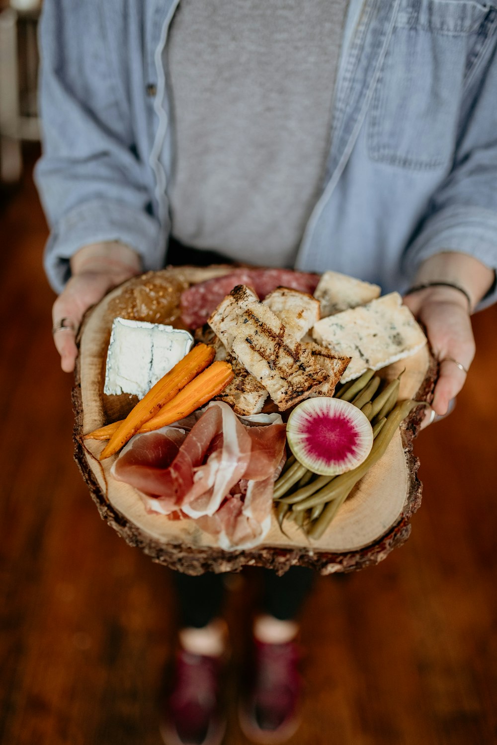 a person holding a platter of meat and cheese