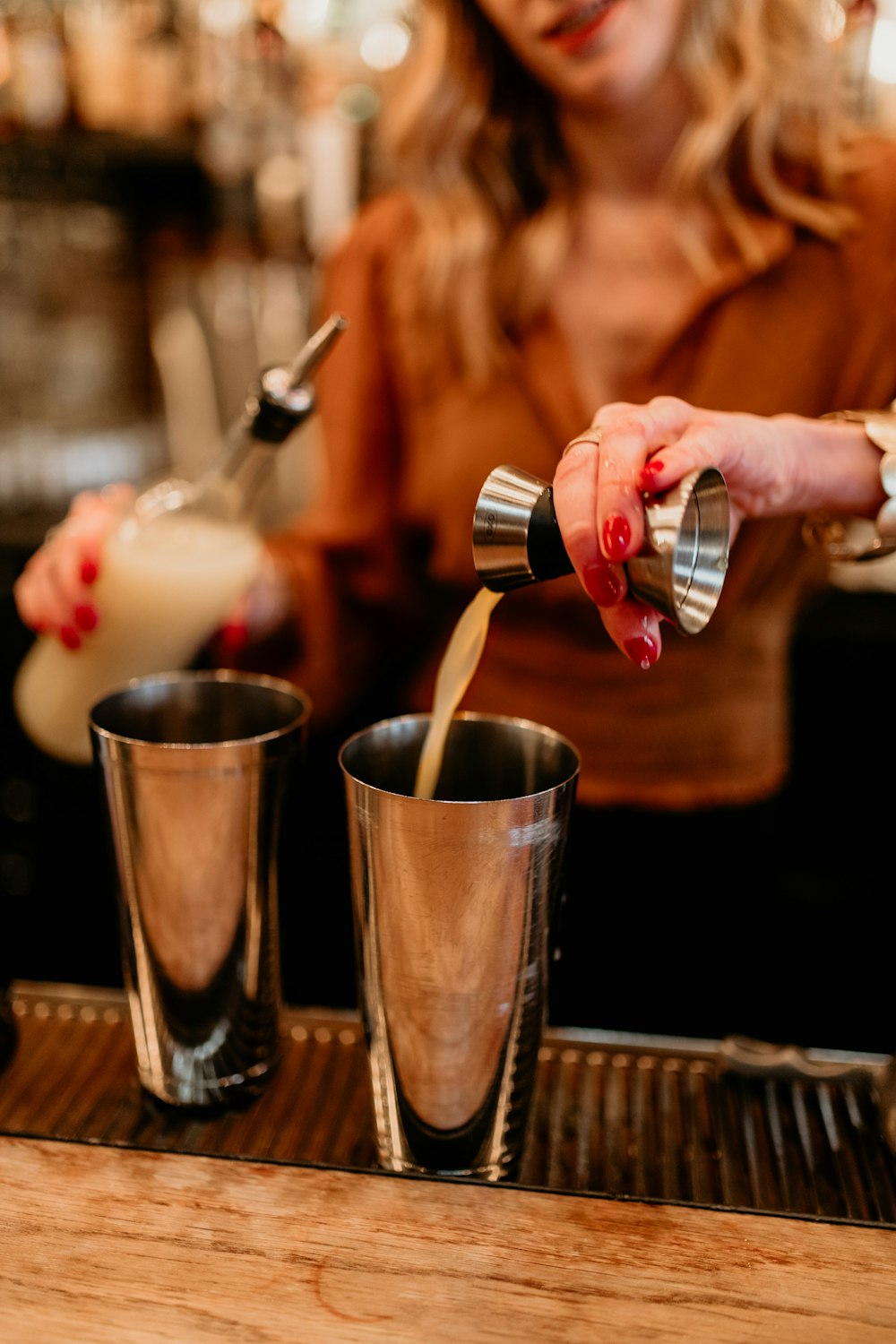 a woman pouring a drink into two shot glasses