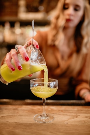 A stylish blonde female bartender expertly mixing a cocktail at a chic private party.