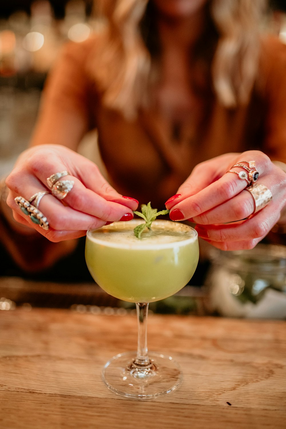 a woman holding a green cocktail in her hands