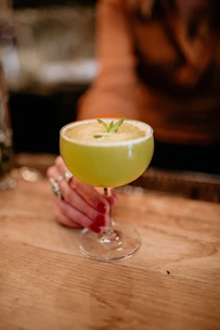 a person holding a glass with a drink in it