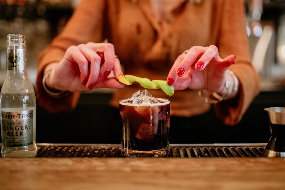 a woman holding a pickle over a drink