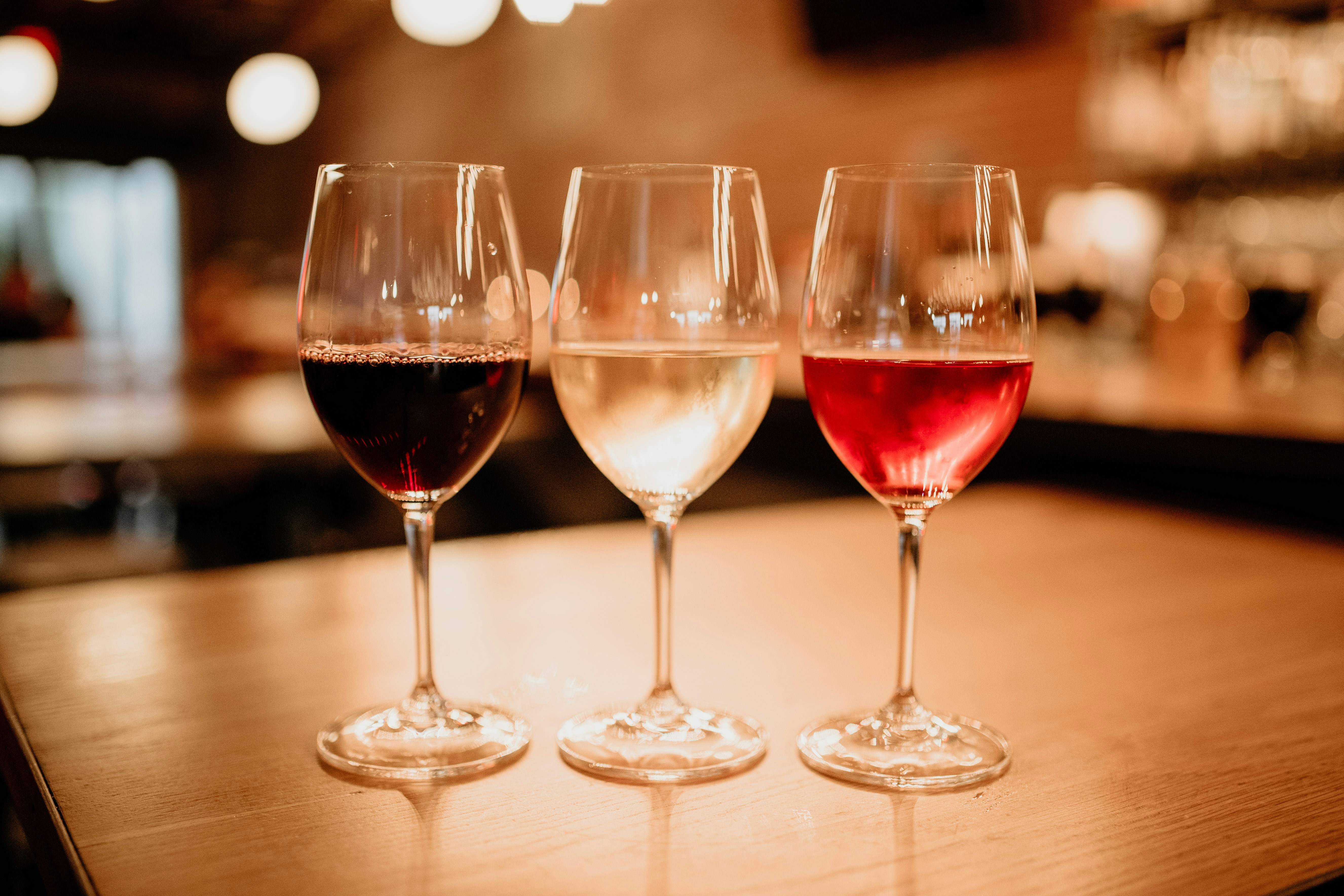 three glasses of wine are sitting on a table, red and white wine