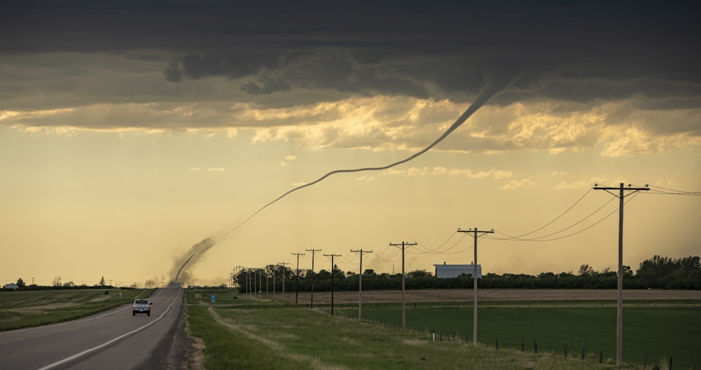 a car driving down a road under a cloudy sky