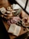 A wooden board displays an assortment of sliced breads, cheese triangles, green beans, cured meats, olives, and a bread roll. The arrangement is artful and appears to be prepared for a charcuterie presentation.