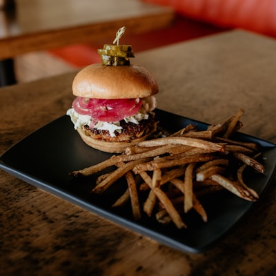 a hamburger and french fries on a black plate