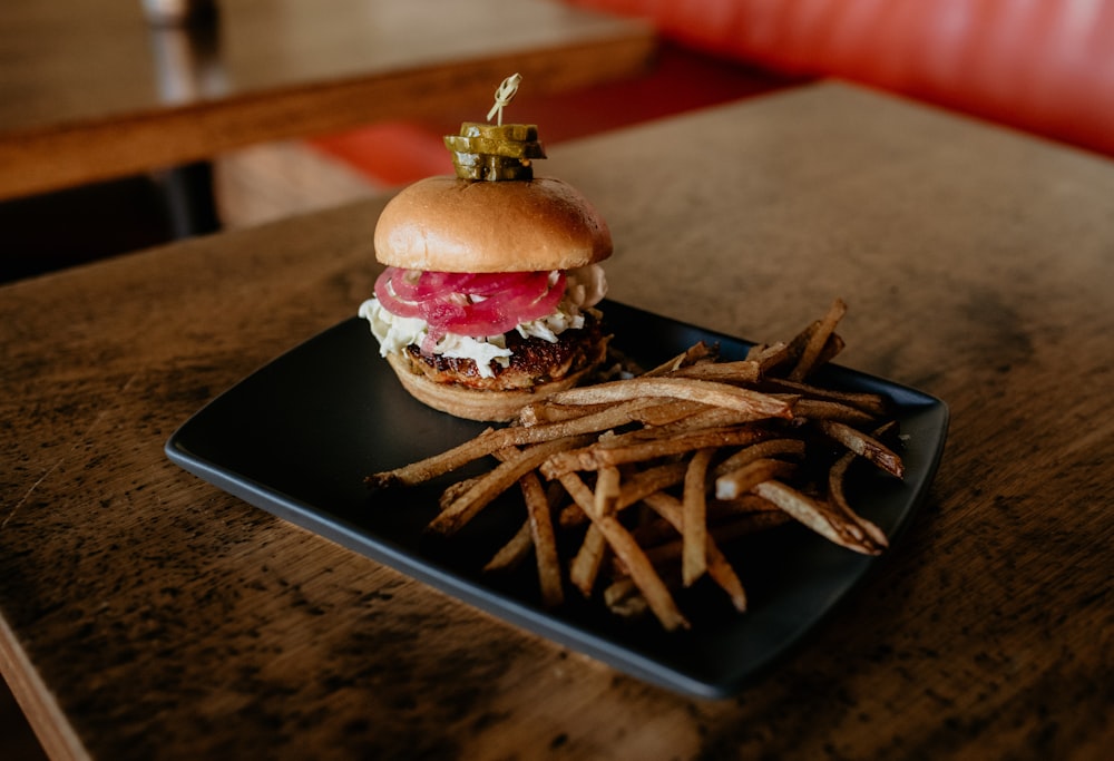 a hamburger and french fries on a black plate