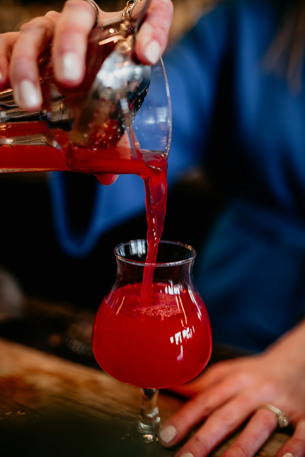 a person pouring a drink into a glass