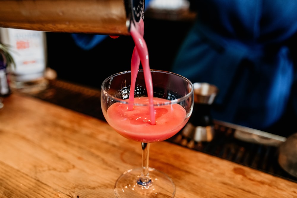 a person pouring a drink into a wine glass