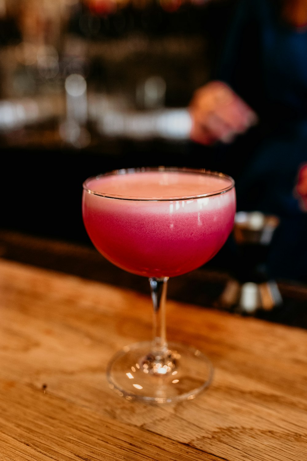 uma bebida rosa sentada em cima de uma mesa de madeira