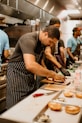 a group of men working in a kitchen preparing doughnuts