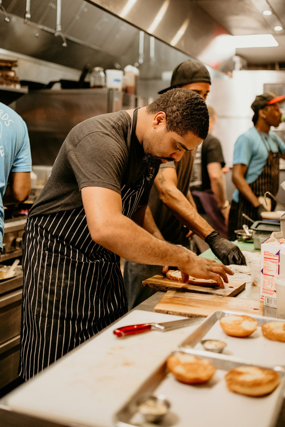 a group of men working in a kitchen preparing doughnuts