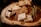 A wooden platter with an assortment of gourmet foods. There are several varieties of cheese, with one piece topped with some blackberries and drizzled with a dark syrup. Additionally, there are green beans laid out alongside honeycomb and toasted bread slices.