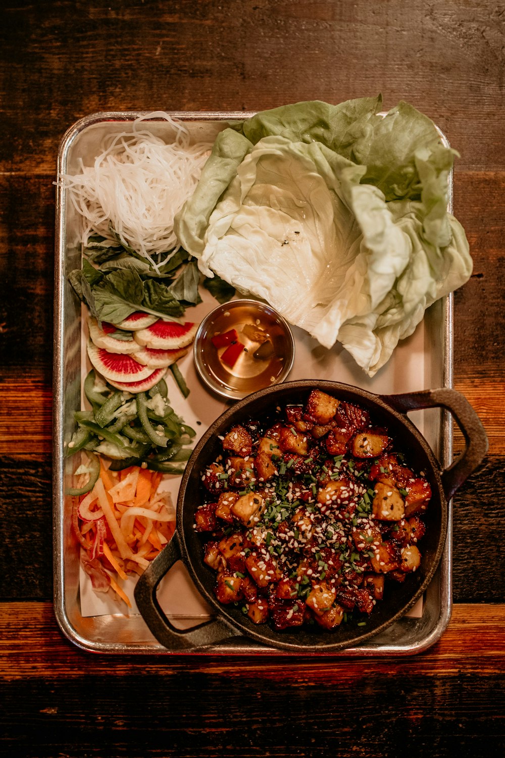 a tray of food that includes lettuce, carrots, and other vegetables