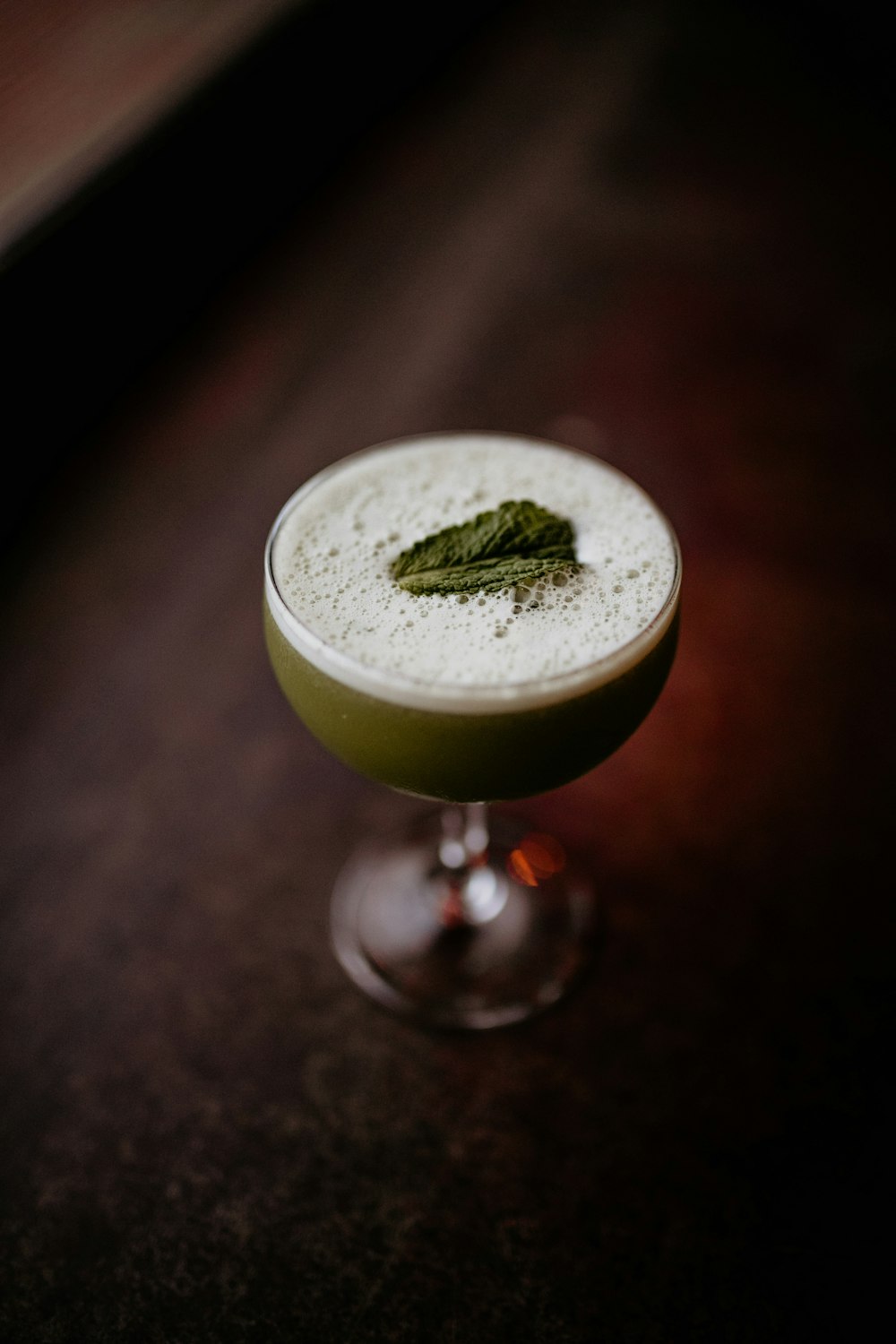 a drink with a green leaf on top of it