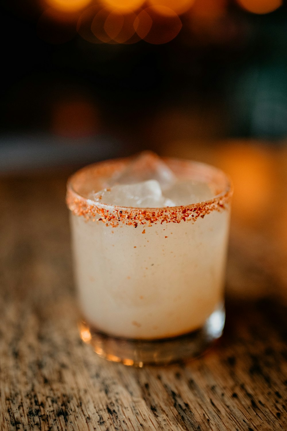 a small glass filled with a drink on top of a wooden table