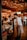 A cozy, warmly lit restaurant interior with a wooden ceiling adorned with string lights. Patrons are engaging in conversation while enjoying their meals. A server, casually dressed, is attentively interacting with a seated couple. The space conveys a lively and inviting atmosphere.