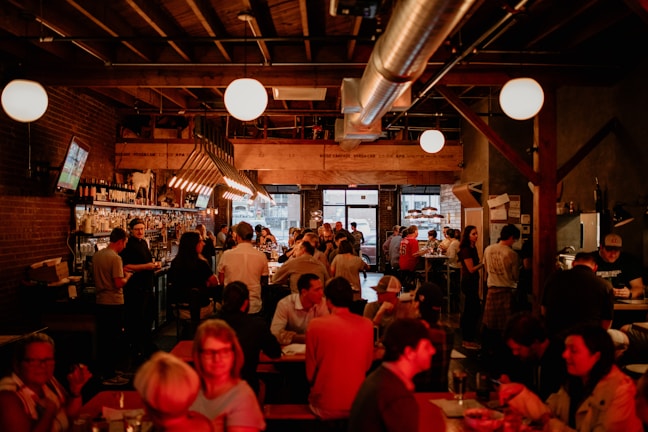 A lively pub scene with friends enjoying burgers and drinks under warm lighting.