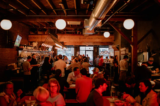 A lively restaurant interior filled with cheering fans watching a big game on multiple screens.