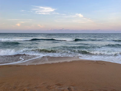 Waves softly crashing on a quiet beach under a pastel sky.