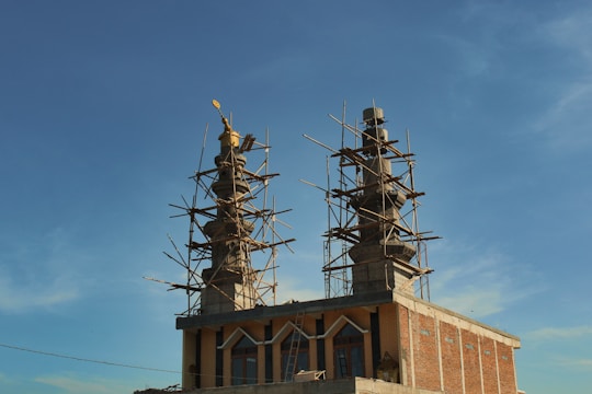Volunteers and builders working side by side to raise walls of a new madarsa building under a bright sky.