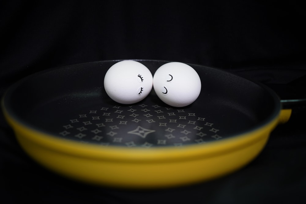 two eggs with faces drawn on them sitting in a frying pan