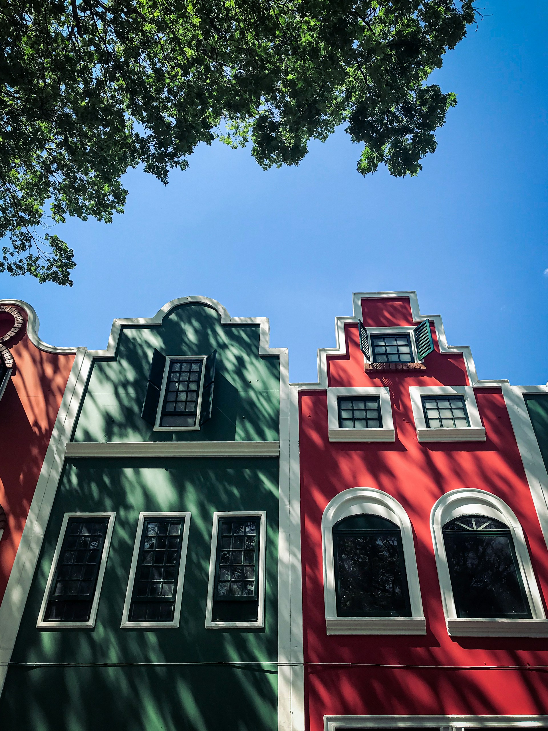 a red and green building with a tree in front of it