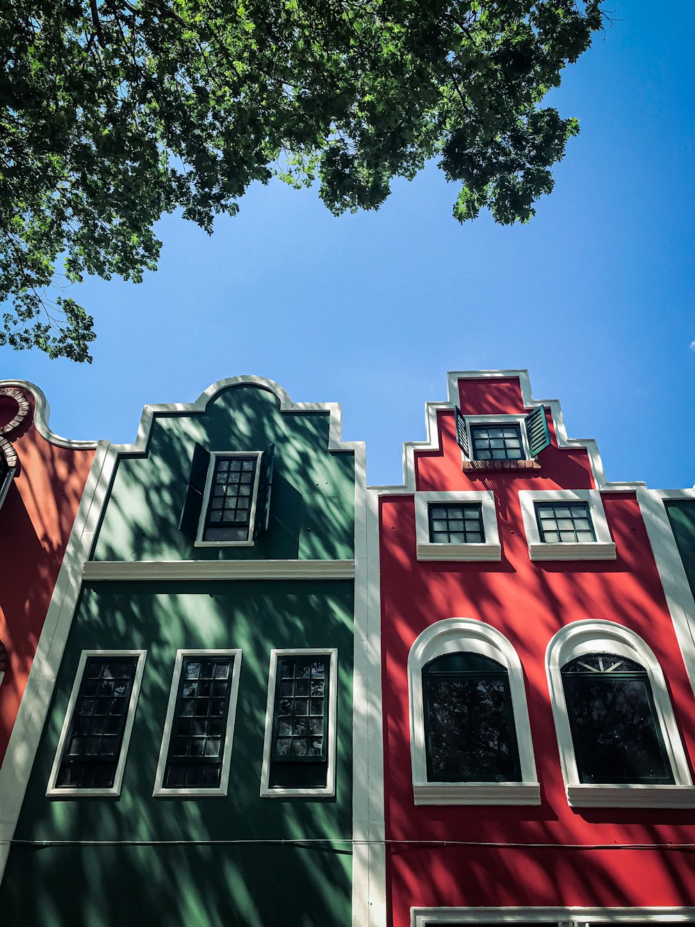 a red and green building with a tree in front of it