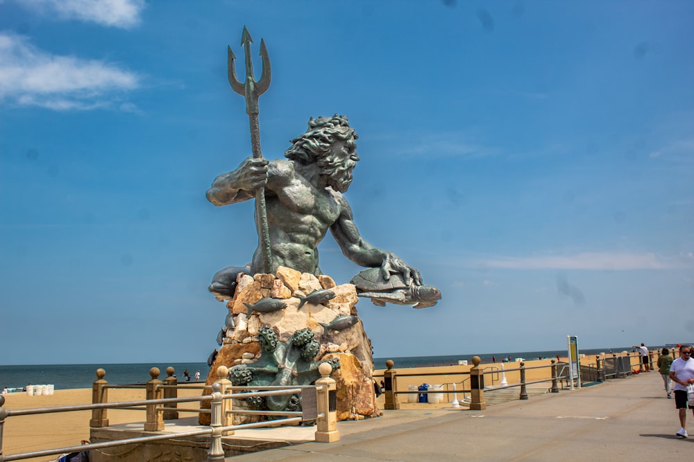 a statue of a man holding a fish near the ocean