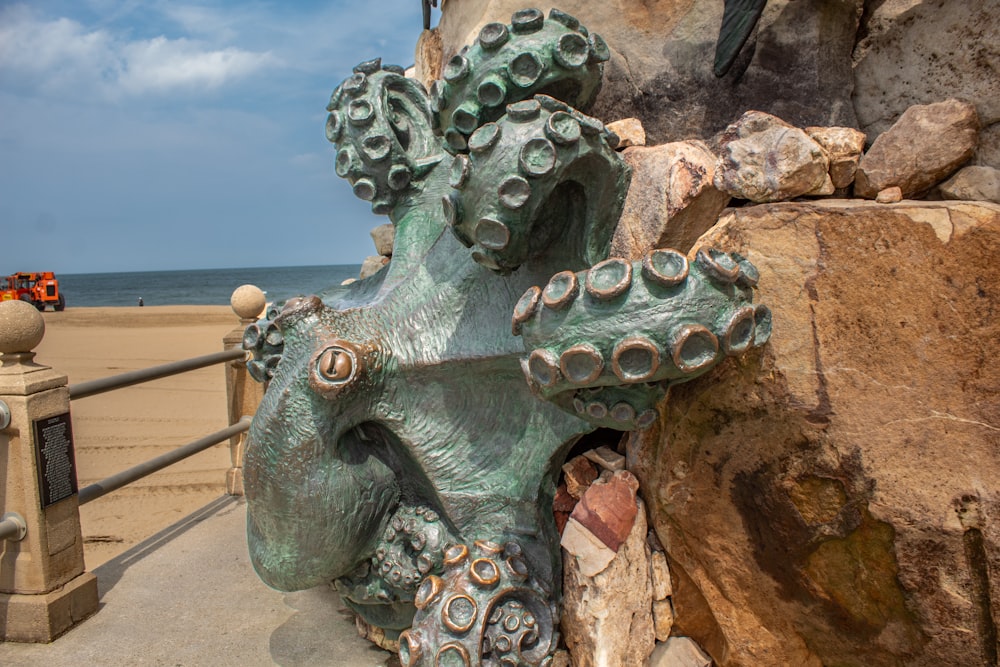 une statue d’une pieuvre sur une plage à côté d’une clôture