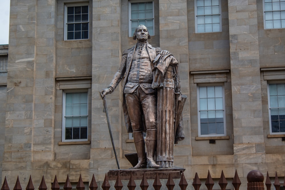 une statue d’un homme debout devant un bâtiment
