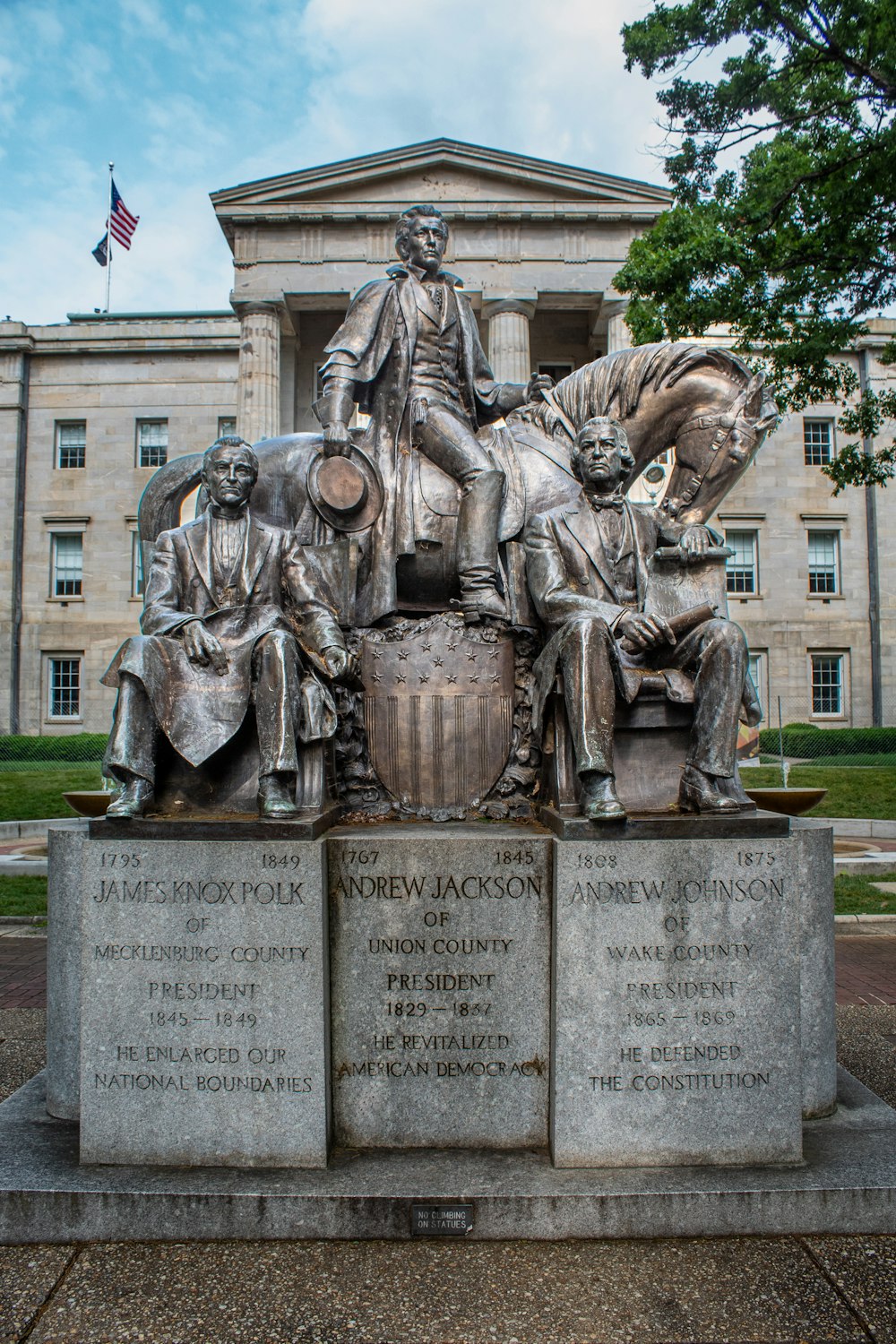 a statue in front of a building with a flag flying in the background