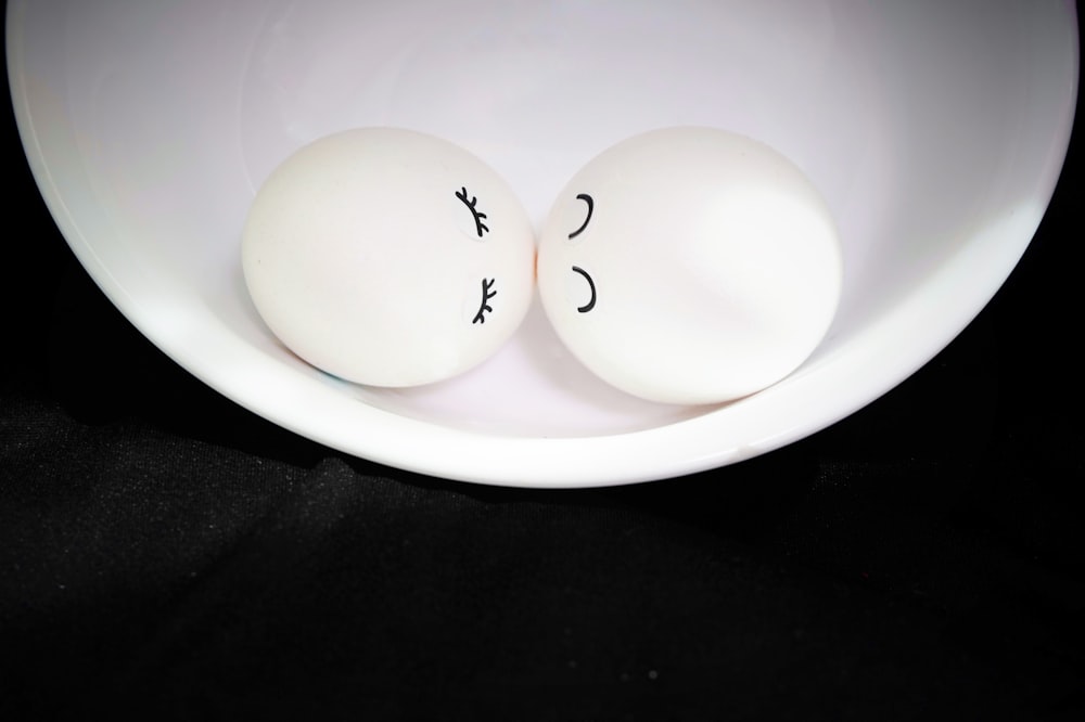 two eggs with faces drawn on them in a bowl