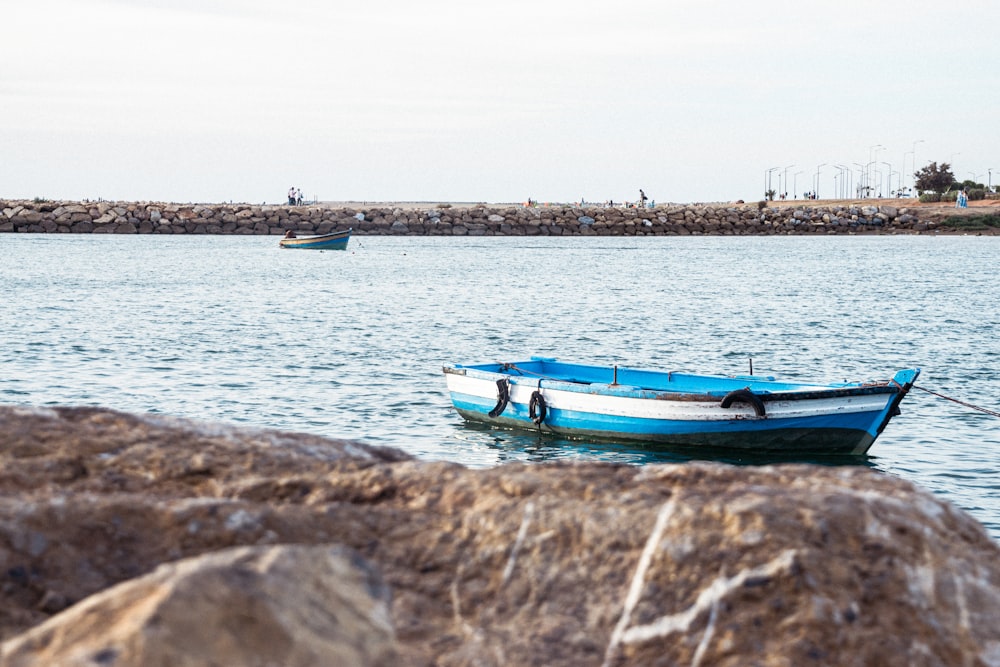 a small blue and white boat floating on top of a body of water