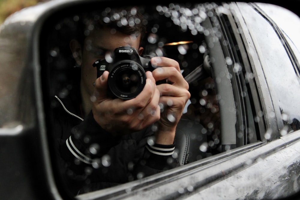 a man taking a picture of himself in a car mirror