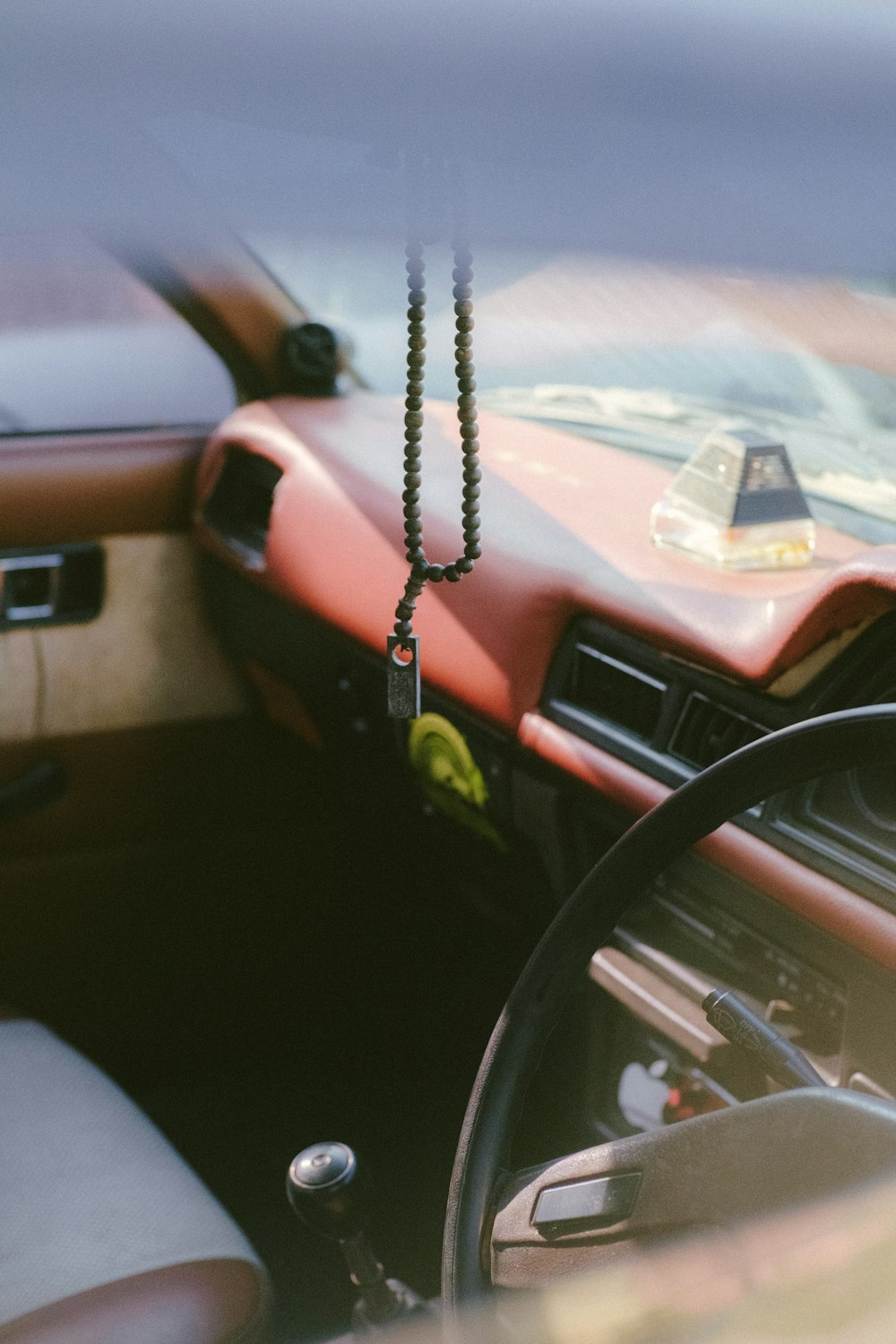 a car dashboard with a steering wheel and a chain hanging from the dash