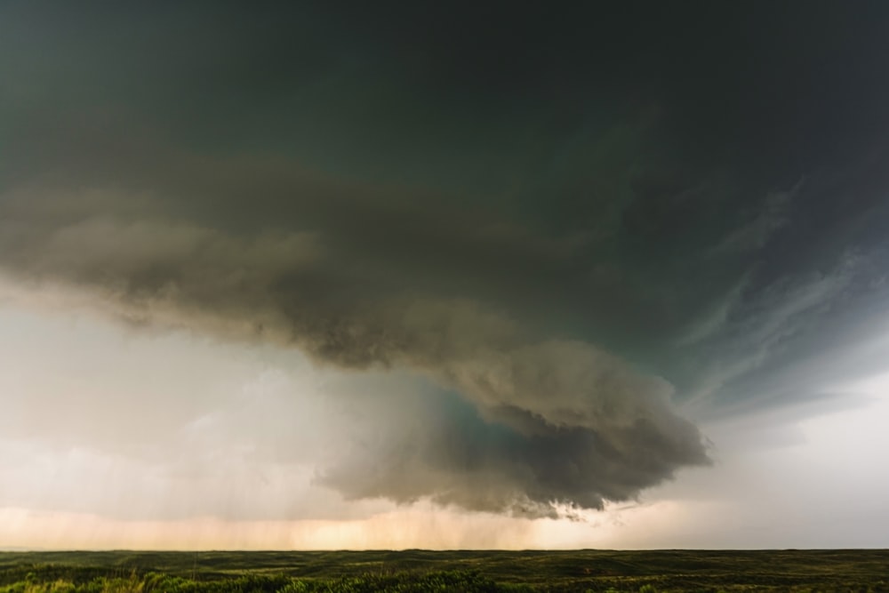 a large storm cloud is in the sky over a field