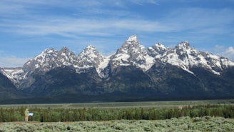 Traveler sketching a custom route on a map with mountains in the background.