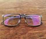 LED-lit smart glasses resting on a reflective surface with purple highlights.